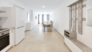 Een moderne keuken met witte kasten, een inbouwoven en een eethoek met een tafel en stoelen.