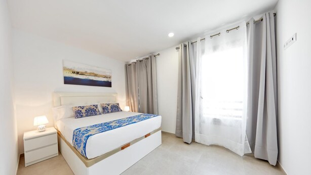 Een moderne slaapkamer met een bed, nachtkastje en een schilderij aan de muur.