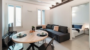 A modern living room with a round wooden table, a sofa, and a bed. - Suite JOIVY Lake 11 (Como)
