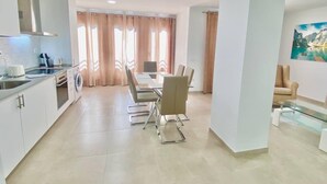 A modern kitchen with a dining area, a sofa, and a painting on the wall. - Deluxe Apartment 100 meters from the beach (Benidorm)