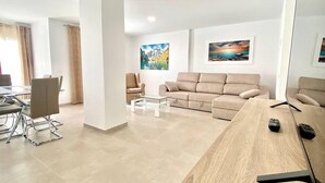 A modern living room with a sofa, coffee table, and a dining area with chairs and a table. - Deluxe Apartment 100 meters from the beach (Benidorm)