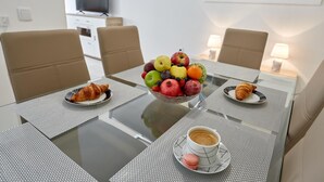 Une table à manger avec un panier de fruits, des croissants et une tasse de café.