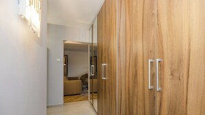 A hallway with a wooden wardrobe, a beige sofa, and a small table. - ShortStayPoland Bohaterewicza B174 (Warsaw)