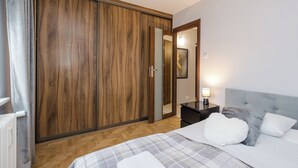 A bedroom with a bed, a nightstand, a mirror, and a wardrobe. - ShortStayPoland Bohaterewicza B174 (Warsaw)