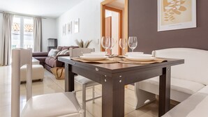 Un coin repas avec une table dressée pour quatre personnes, un canapé et un téléviseur en arrière-plan.