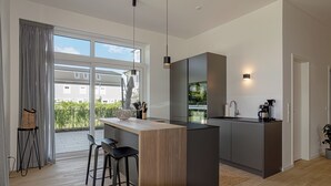 Una cocina moderna con una isla central, taburetes de bar y vistas al exterior.