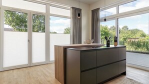 Cocina moderna con encimera de madera, armarios negros y vistas al exterior.