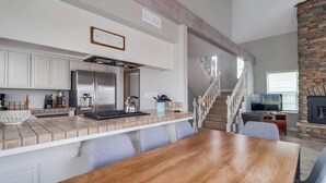 Una cocina moderna con armarios blancos, un refrigerador de acero inoxidable y una chimenea de piedra.