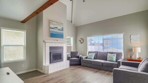 A living room with a fireplace, grey sofas, and a white coffee table. - Steps to bay & ocean, Belmont Park, A/C family fun (San Diego)