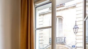 Una stanza con una finestra che dà su un edificio con un balcone e un numero '14'.