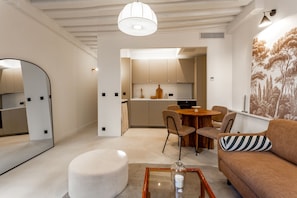 Una sala moderna con una mesa redonda, un sofá con cojín a rayas, y un comedor con sillas y una mesa de madera.
