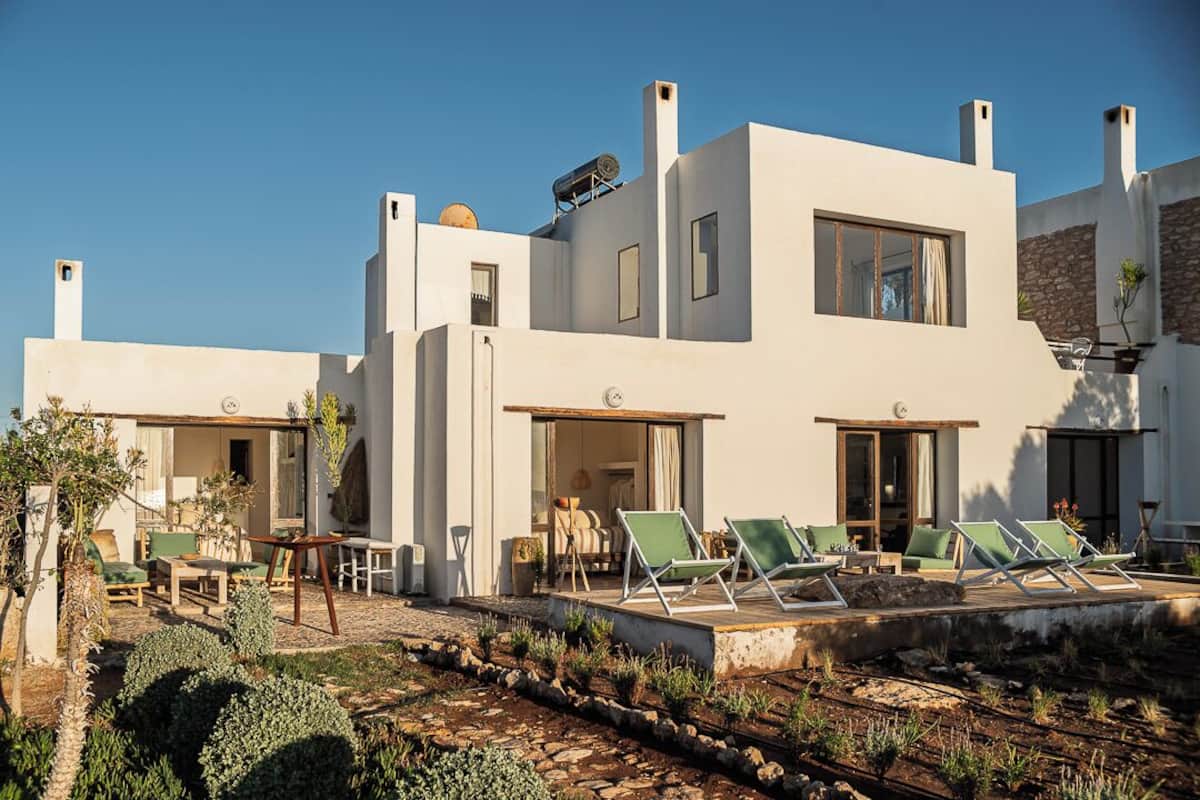 A modern villa with a patio, outdoor seating, and a pool area.