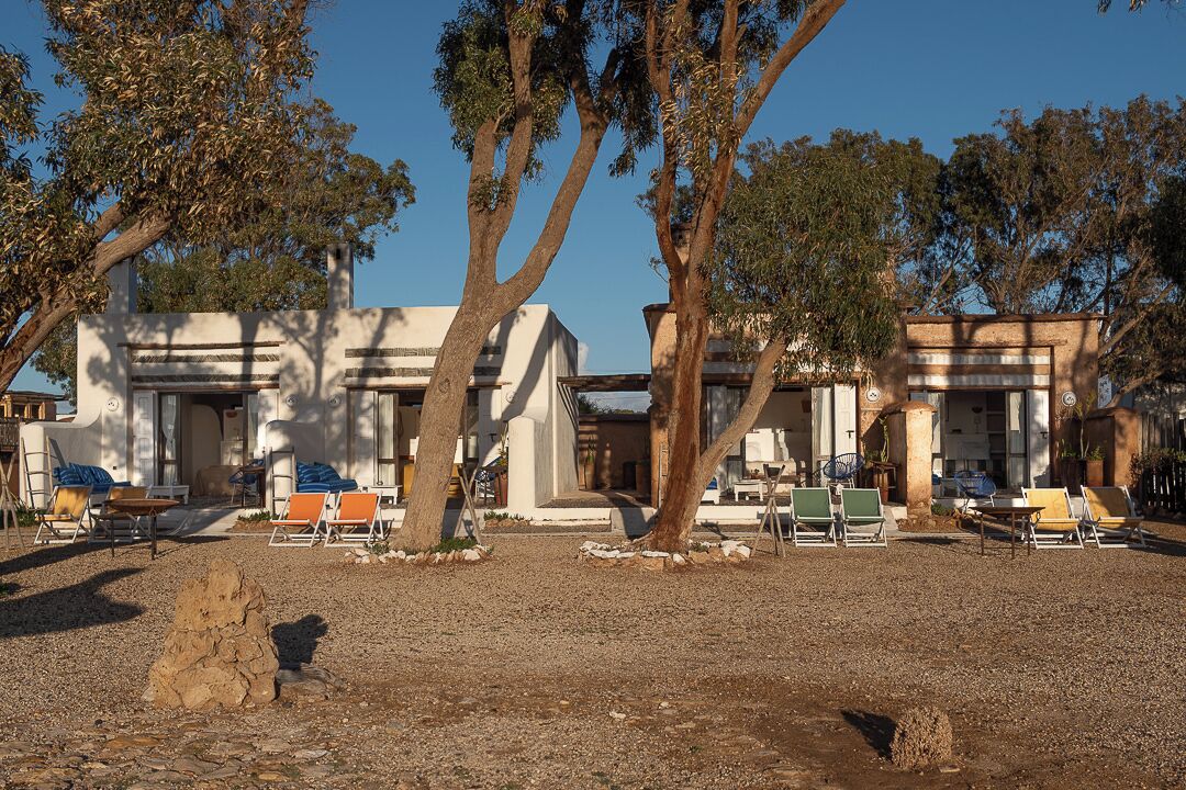 Un edificio con varias habitaciones, mesas al aire libre y árboles.
