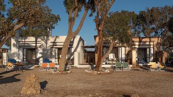 Un edificio con varias habitaciones, mesas al aire libre y árboles.