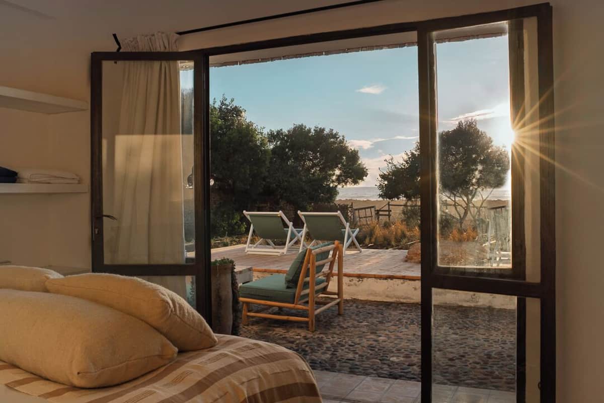 A bedroom with a large sliding glass door leading to an outdoor seating area with two chairs and a table.