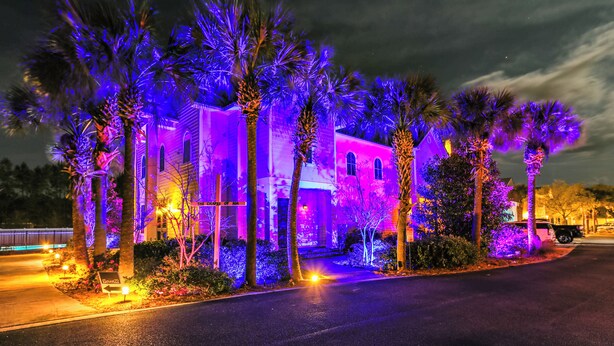 A building with a symmetrical facade, multiple windows, and a well-maintained lawn with palm trees.