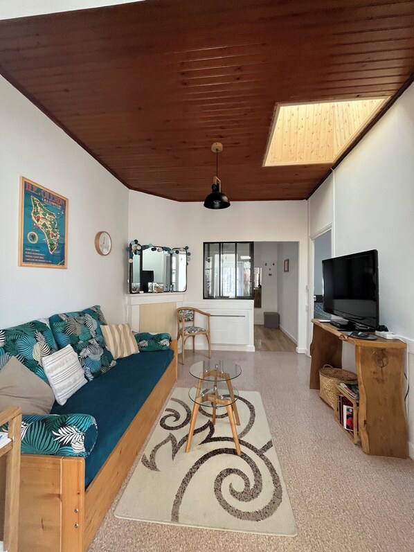 A living room with a sofa, a glass coffee table, a TV, and a wooden cabinet.