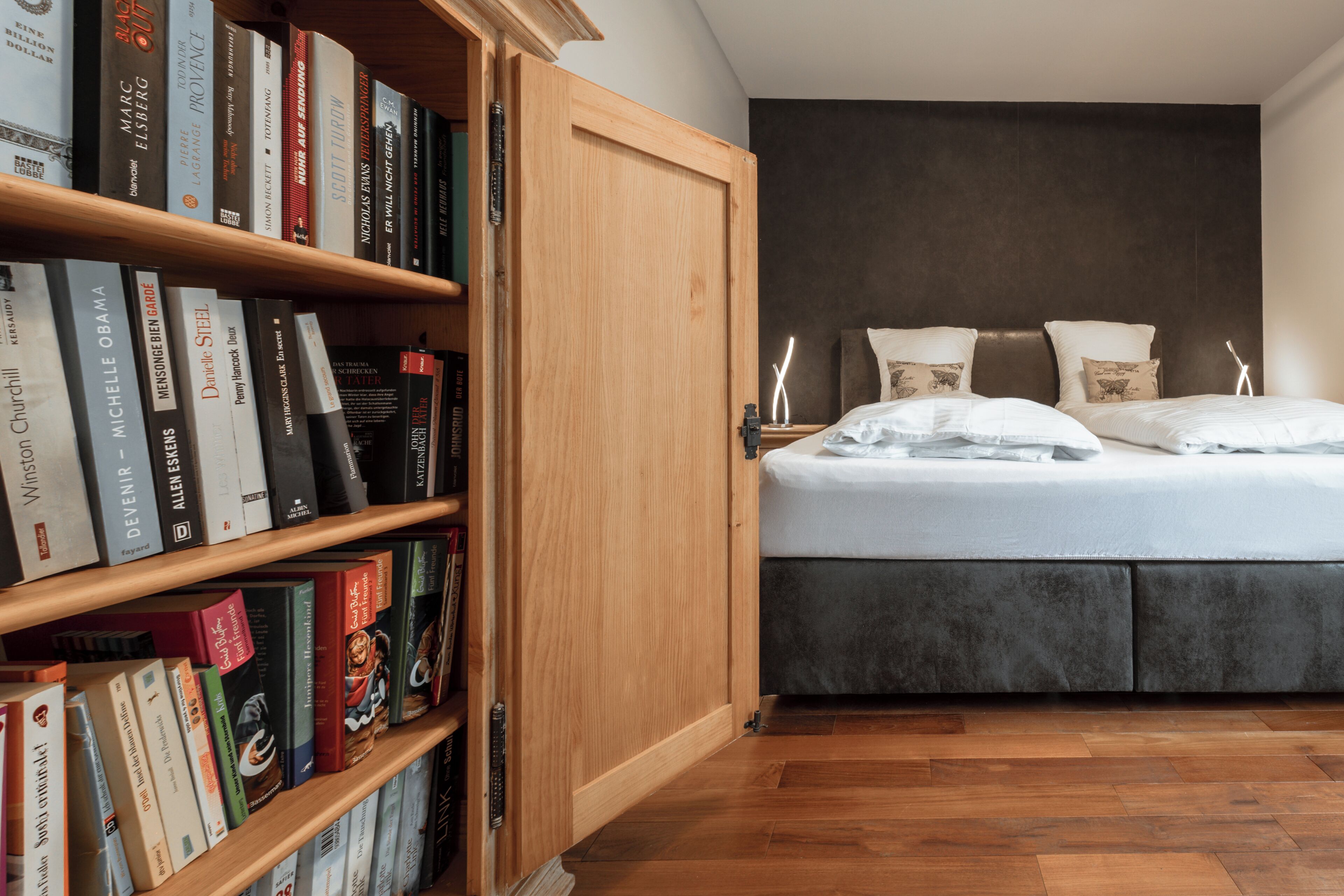 Une chambre à coucher avec un lit, une bibliothèque en bois et une armoire.