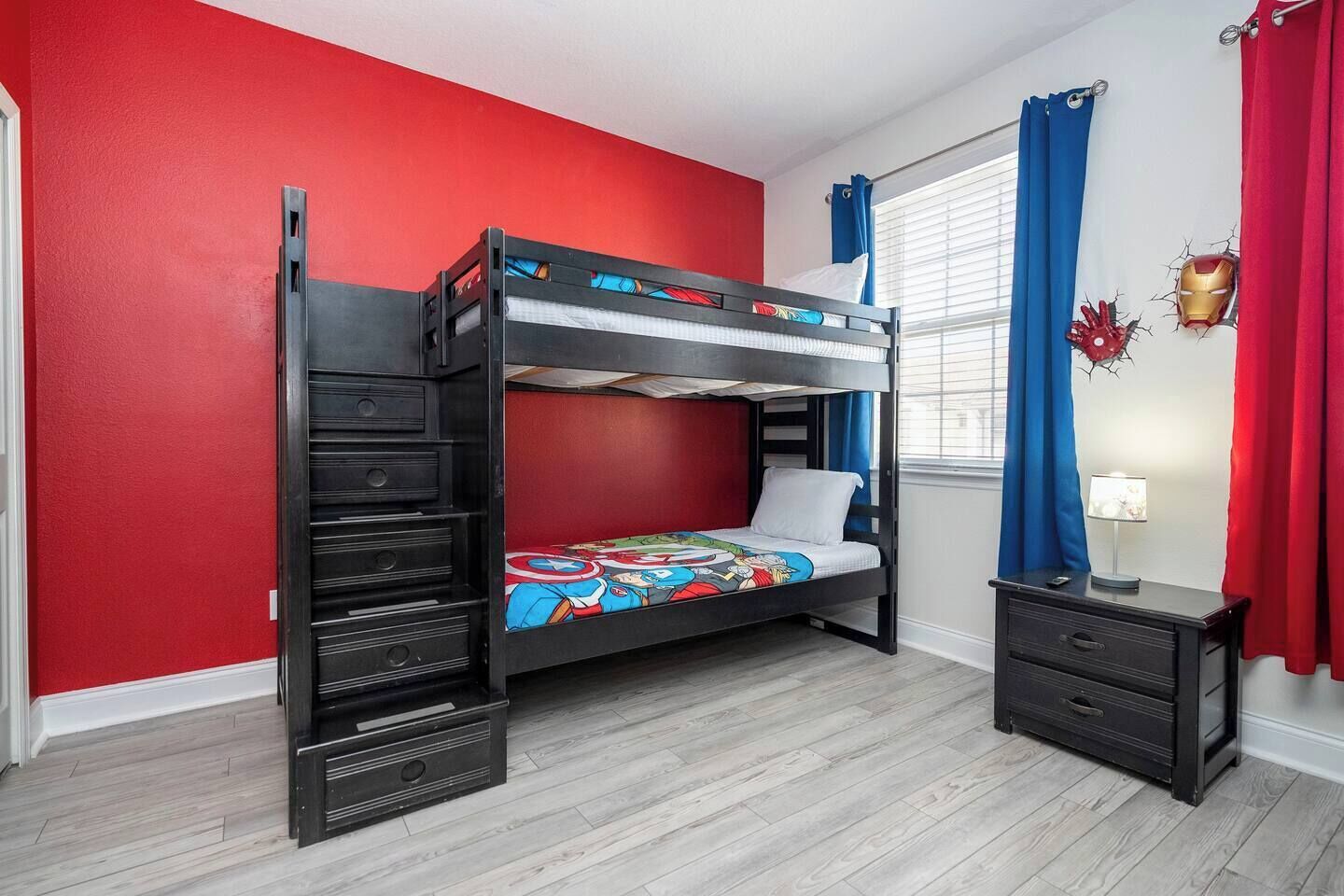 A bunk bed with a colorful bedspread, a dresser, and a window with curtains.
