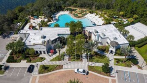 Vista aérea de un complejo turístico con piscina, campo de golf y aparcamiento.