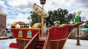 Zona de juegos acuáticos con forma de barco pirata de madera y escaleras para subir.