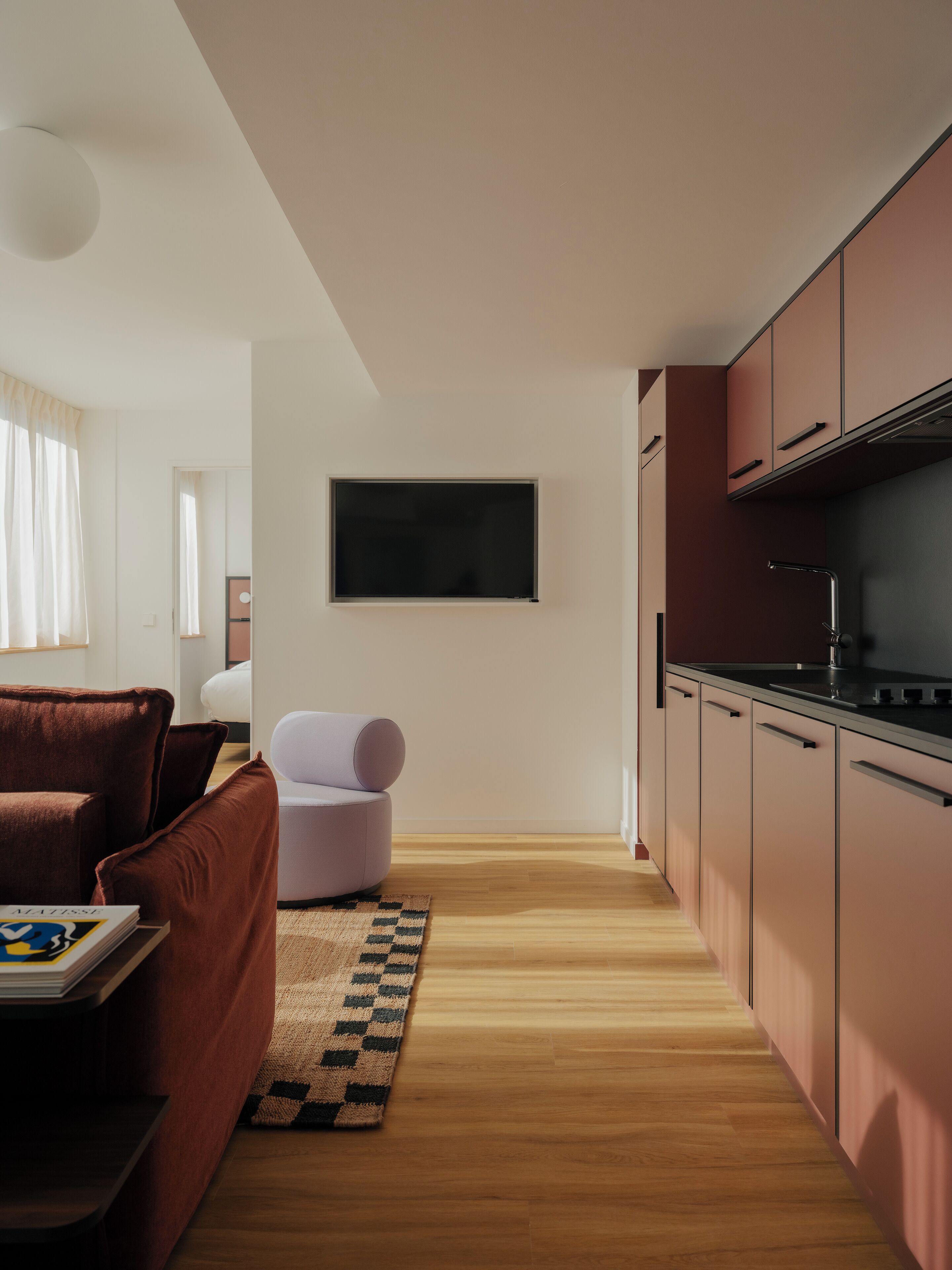 A modern kitchen with wooden flooring, a built-in oven, and a large window.