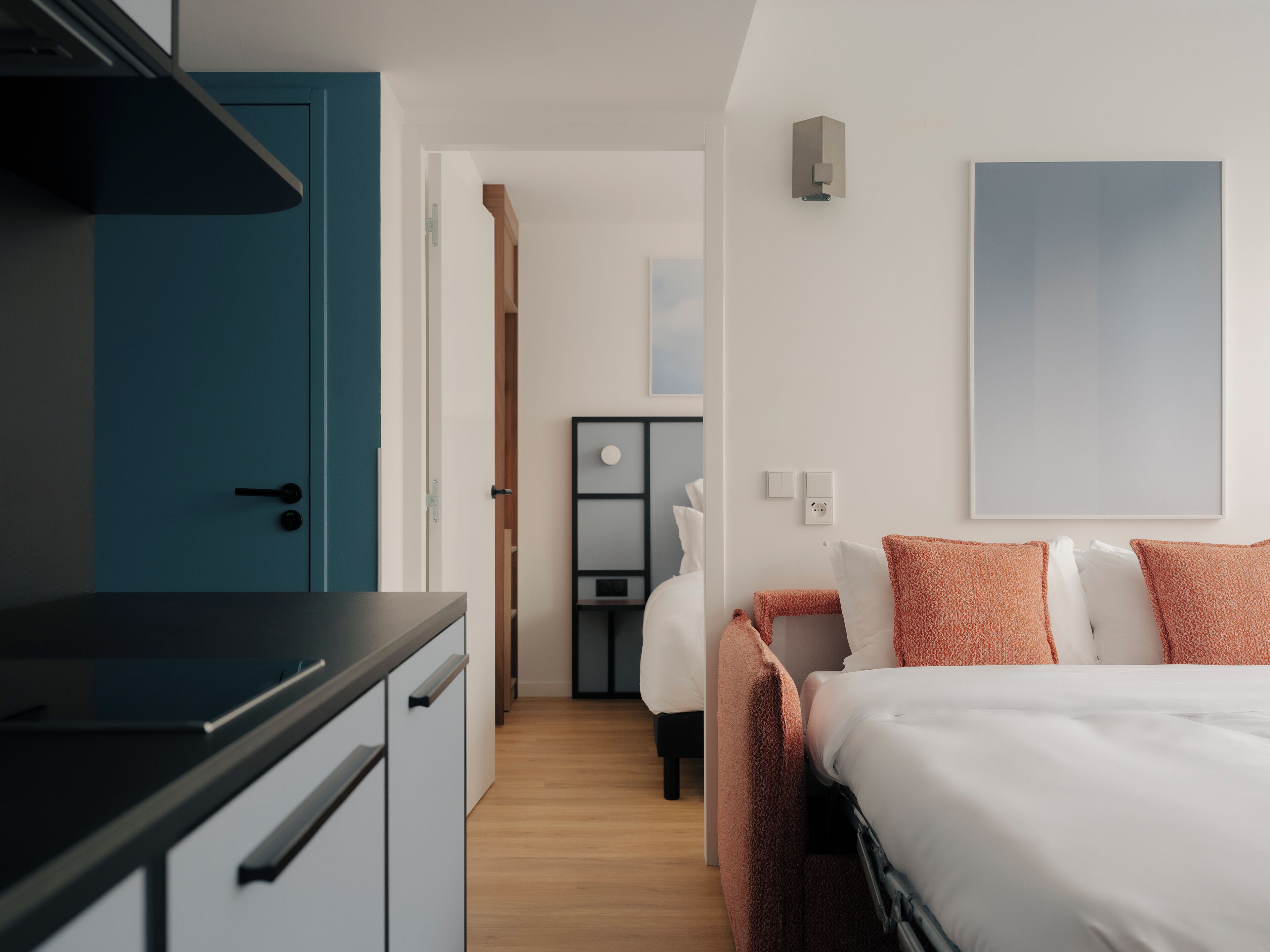 A modern hotel room with a bed, a desk, and a wardrobe.