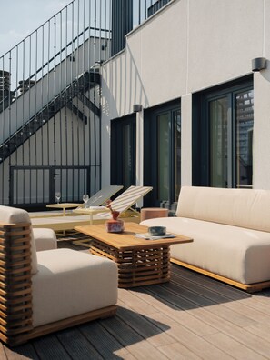Una zona relax all'aperto, moderna, con divano, poltrone e tavolino.