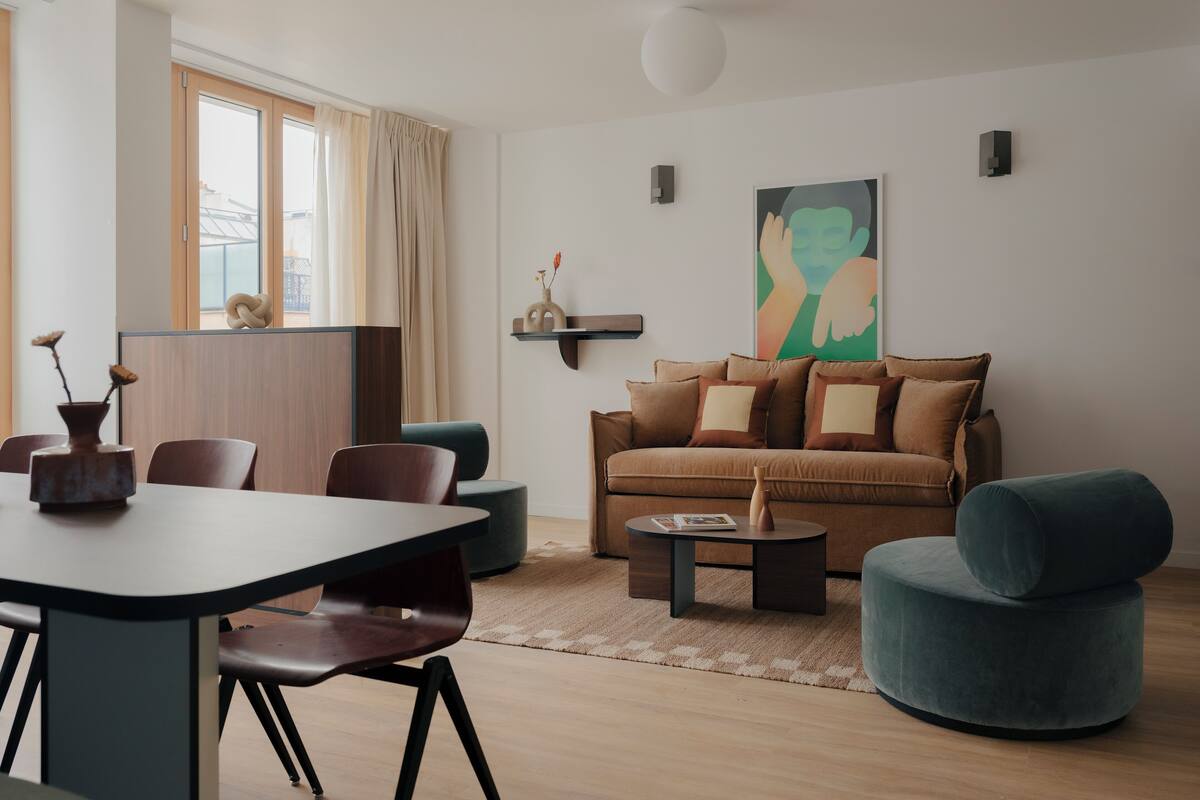 Un salon moderne avec un coin repas, comprenant un canapé, des fauteuils, une table basse et une table à manger.