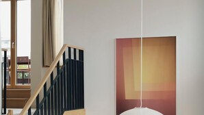 Un intérieur moderne avec un escalier, un luminaire suspendu et un tableau accroché au mur.