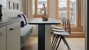 Une cuisine moderne avec un coin repas, comprenant une table avec des chaises, un vase et un canapé avec des coussins.