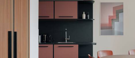 A modern kitchen with wooden cabinets, a black countertop, and a dining area with a round table and chairs.