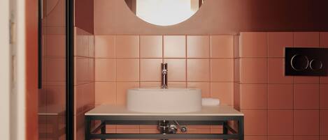 A modern bathroom with a round mirror, white sink, and a towel on the counter.