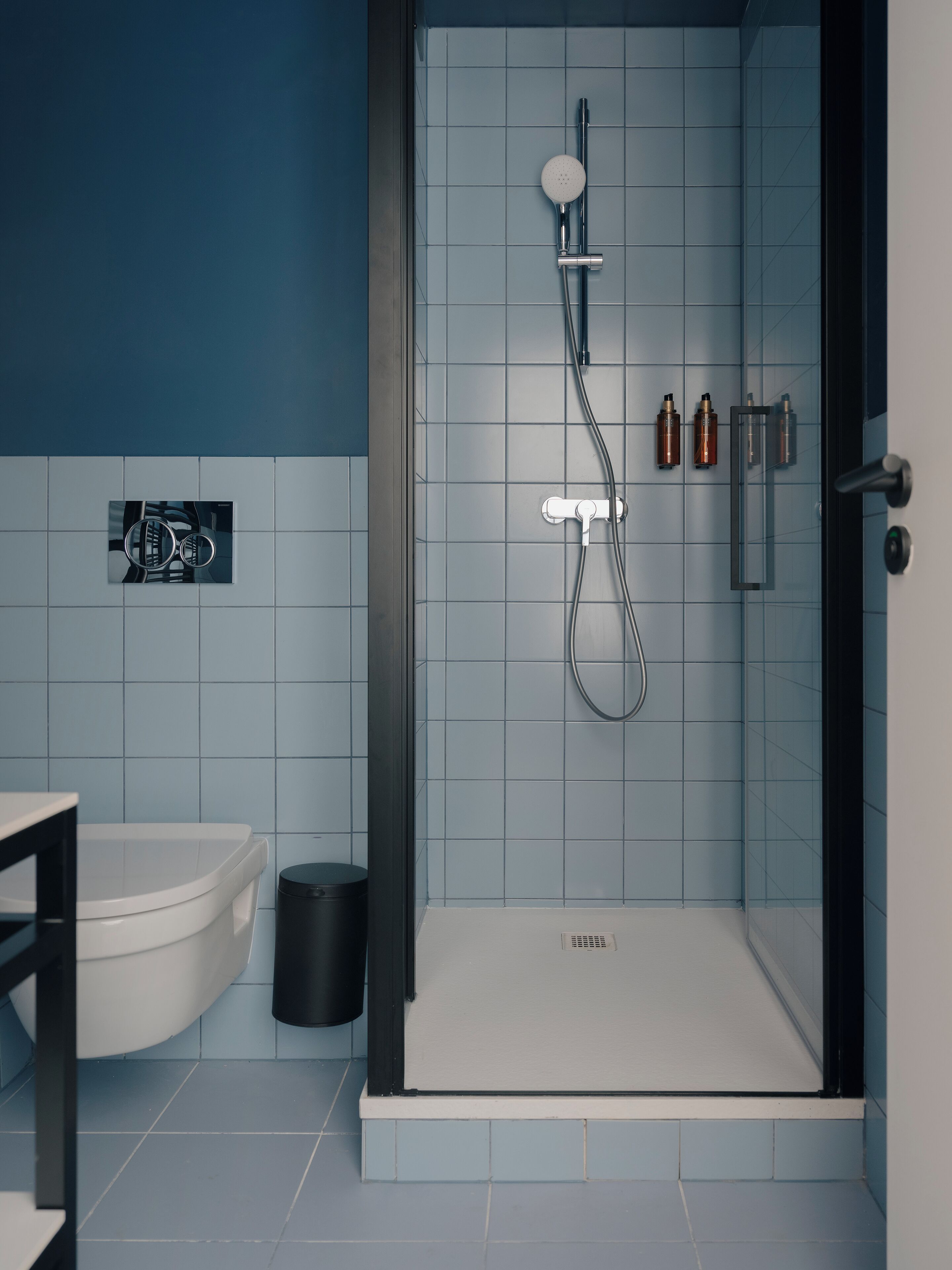 A modern bathroom with a glass-enclosed shower, a toilet, and a sink.