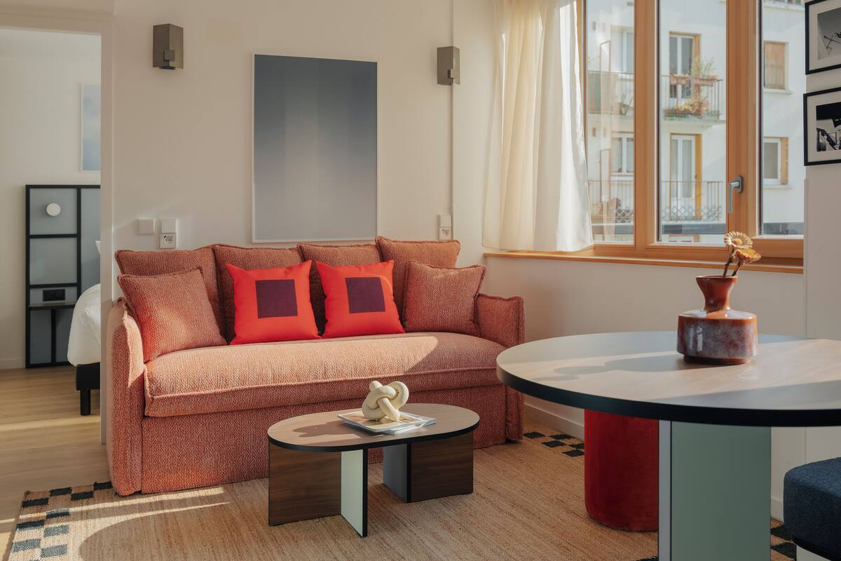 Un salon moderne avec un canapé, une table basse ronde et une fenêtre avec des rideaux.
