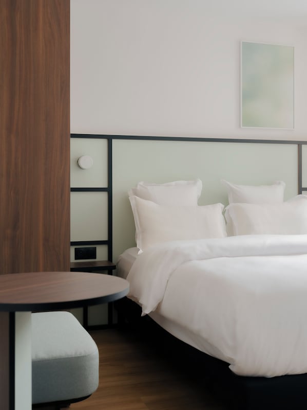 A neatly arranged hotel room with a bed, bedside table, and a small seating area.