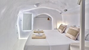 Un dormitorio acogedor, decorado en blanco, con una cama, almohadas y una ventana.