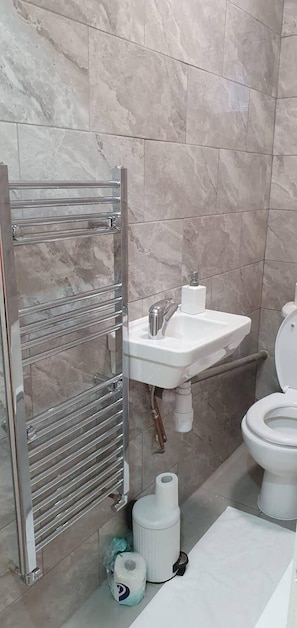 A bathroom with a marble floor, a white sink, a toilet, and a towel rack.