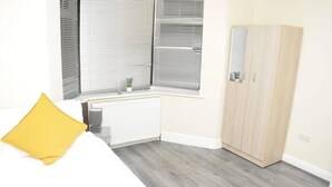 A bedroom with a bed, a radiator, a wardrobe, and a window with blinds. - 4 Bedroom House in Grays - Sleeps 6 & Parking (Grays)