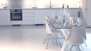 Une cuisine moderne avec des meubles blancs, un four encastré et un four à micro-ondes.