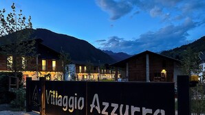 A sign for Villaggio Azzurro with a view of mountain houses at dusk. - In the heart of the Ledro Valley, where nature sets the pace. (Trentino-Alto Adige)