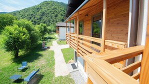 A wooden cabin with a balcony overlooking a grassy area and a mountain in the background. - In the heart of the Ledro Valley, where nature sets the pace. (Trentino-Alto Adige)