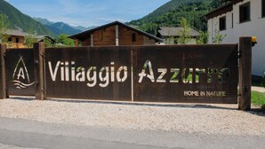 A rustic metal gate with the text "Viliaggio Azzuto" and "HOME IN NATURE" indicating a nature-focused lodging area. - In the heart of the Ledro Valley, where nature sets the pace. (Trentino-Alto Adige)