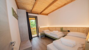 A modern bedroom with two beds, wooden ceiling beams, a small window, and a door. - In the heart of the Ledro Valley, where nature sets the pace. (Trentino-Alto Adige)