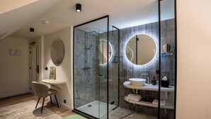 Un baño moderno con ducha de vidrio, espejo redondo y tocador con lavamanos.