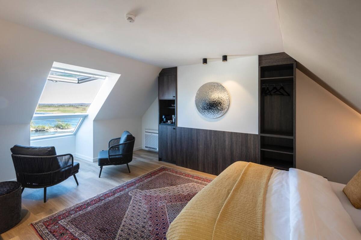 A modern bedroom with a large bed, a chair, a wardrobe, and a circular wall decoration.