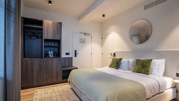 A modern bedroom with a large bed, a wardrobe, and a wall-mounted artwork.