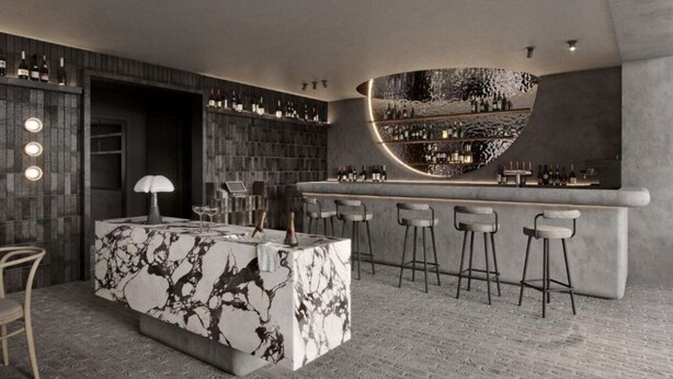 Un moderno bar con mostrador de mármol, varios taburetes y una estantería con botellas de vino.