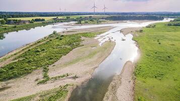 Un fiume sinuoso che serpeggia attraverso un paesaggio rurale, con turbine eoliche visibili in lontananza.