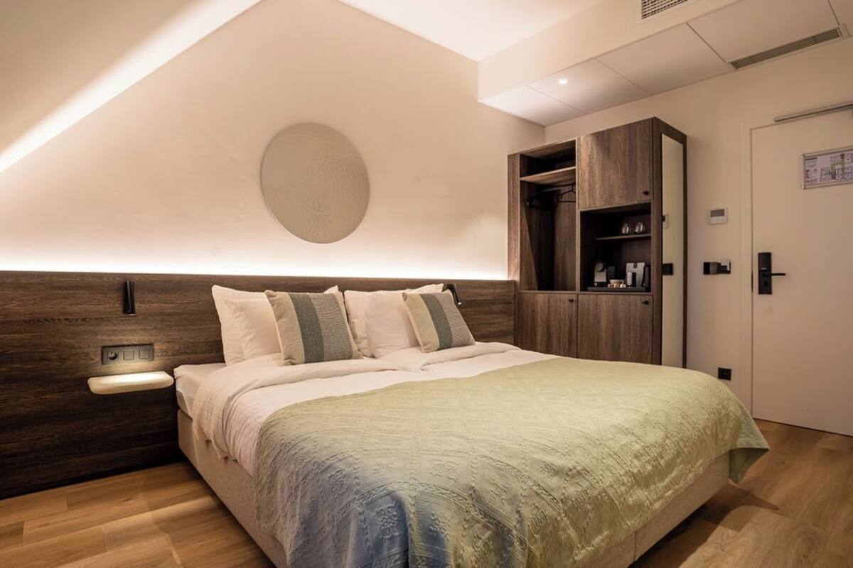 A modern bedroom with a large bed, wooden headboard, bedside table, and built-in wardrobe.